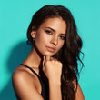 © Dmitry Tsvetkov - Young sexy slim tanned woman in black swimsuit posing against blue background. Closeup Fashion portrait of beautiful girl with long wavy brunette hair. Swimwear or bikini model