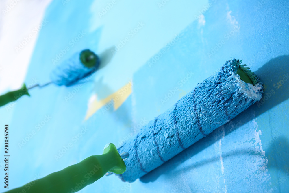 Painting wall with rollers indoors