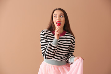 Sticker - Attractive young woman with lollipop on color background