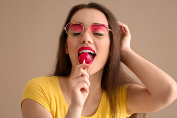 Sticker - Attractive young woman with lollipop on color background