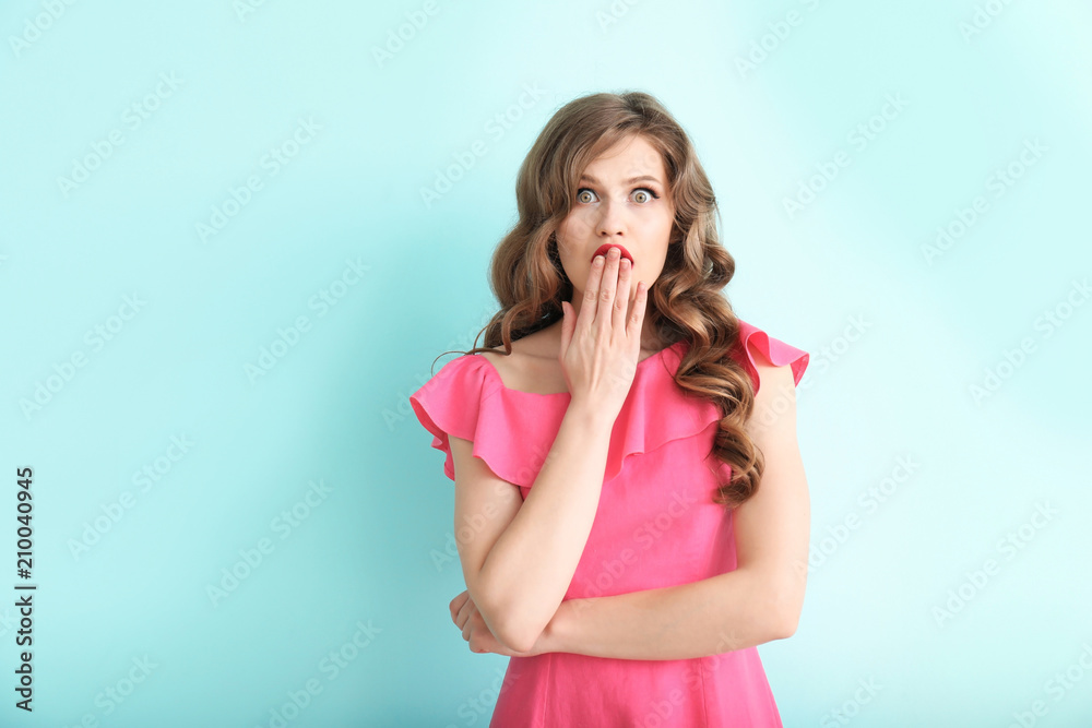 Shocked young woman on color background
