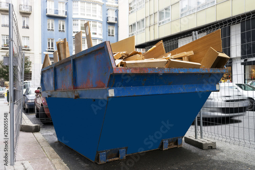 Fotografía metal container with debris and wood waste in city street