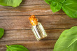 © detry26 - A bottle of basil essential oil with fresh basil leaves on a table.