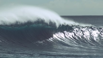 Wall Mural - SLOW MOTION, CLOSE UP: Epic emerald ocean wave splashing wildly near black rocky shore of Easter Island. Glassy water droplets glimmer in the bright summer sun. Barrel wave approaching tropical island