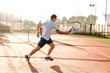  Man playing tennis in the morning in sunlight running
