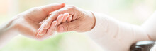 Close-up Of Tender Gesture Between Two Generations. Young Woman Holding Hands With A Senior Lady. Blurred Background. Panorama.