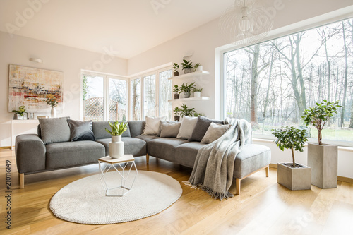 Blankets and cushions on a grey corner sofa standing in white