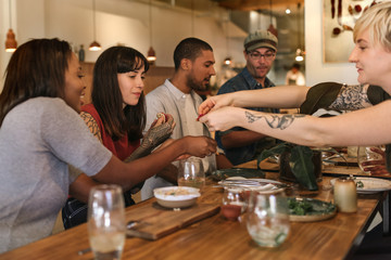 Wall Mural - Diverse friends sharing delicious food together in a bistro