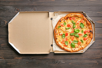 Carton box with delicious pizza Margherita on wooden background