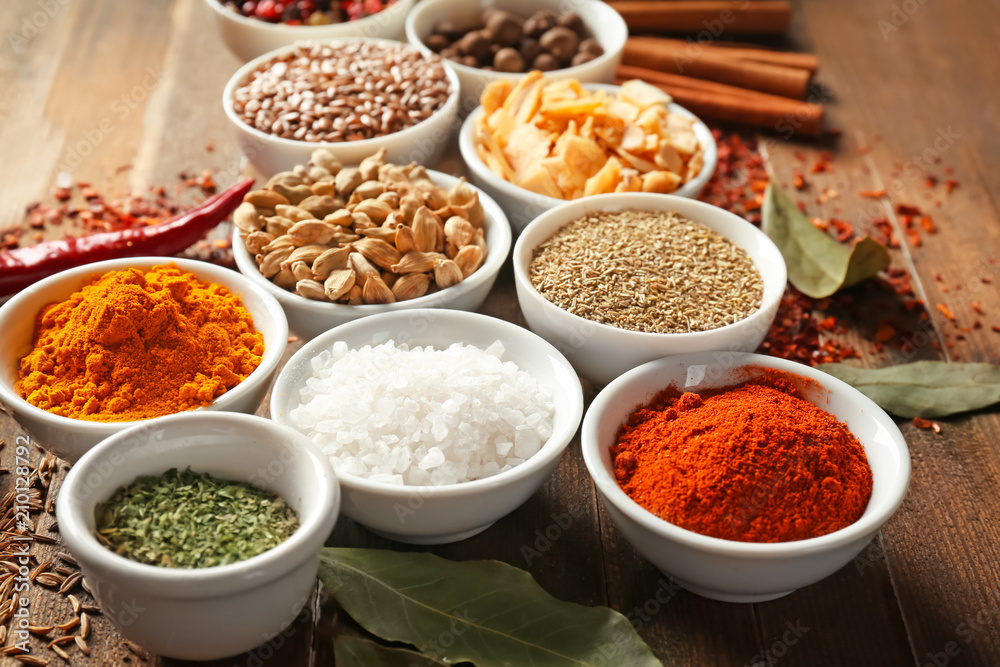 Bowls with various spices on wooden background