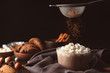 Sprinkling of hot drink with cacao powder on dark background
