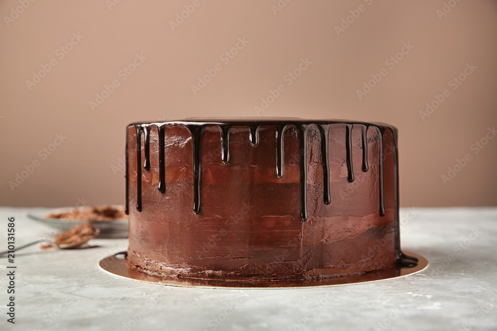 Plate with delicious chocolate cake on table against color background