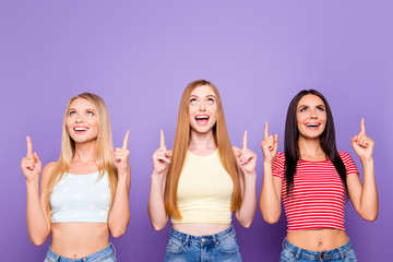 Wall Mural - Portrait with copyspace for product of glad fancy girls gesturing empty place with forefingers looking up isolated on vivid violet background