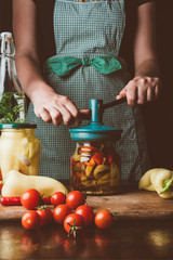 cropped image of woman preparing preserved vegetables in glass jar at kitchen