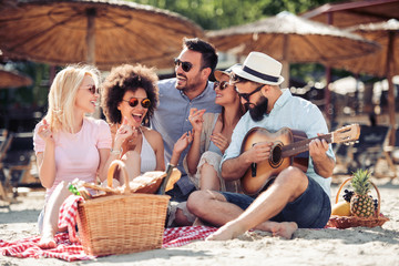 Group of happy young people having a picnic on the beach