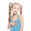 Young seven years old girl in blue dress on a white isolated background. Delightful, joyful emotions on her face, makes yummy, hungry gersture with her hands and face, licking her lips with tongue