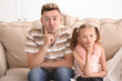 © Pixel-Shot - Funny father and daughter sitting on sofa at home
