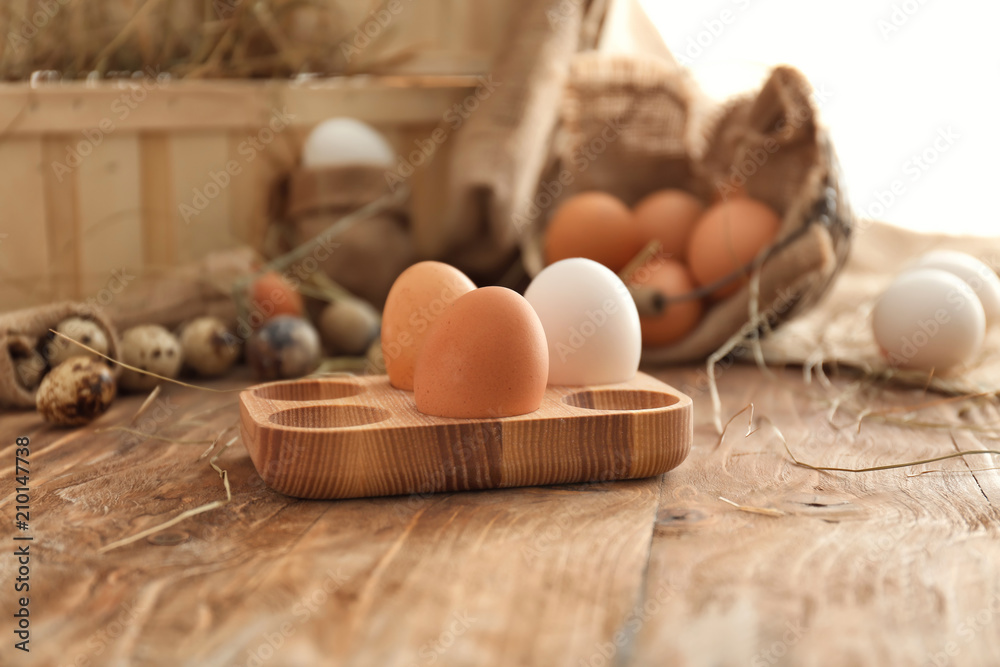 Wooden holder with chicken eggs on table