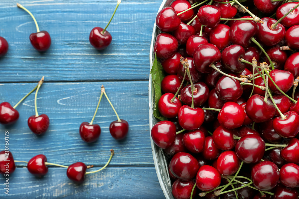 Bowl with tasty cherries on wooden table, top view