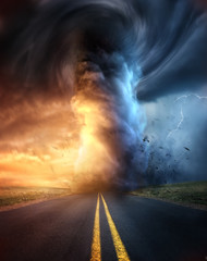 a powerful supercell storm at sunset producing a huge and destructive tornado touching down on a hig