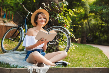 Wall Mural - Smiling young girl reading a book while resting