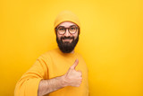 Fototapeta  - Content guy with thumb up on yellow