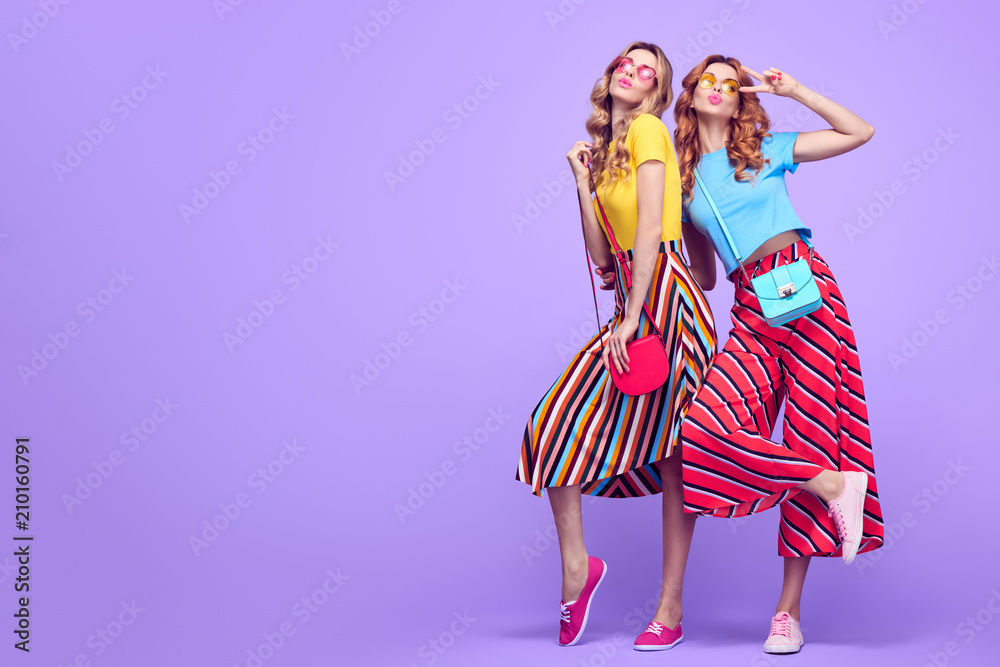Full-length portrait Two Girls with Wavy Hairstyle Having Fun Dance. Young Beautiful Pretty Model Woman in Striped Fashion Stylish Summer Outfit. Crazy Sisters Friends on Purple - obrazy, fototapety, plakaty 