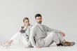 © LIGHTFIELD STUDIOS - couple of attractive models in vintage clothes sitting on floor and leaning back to back on white
