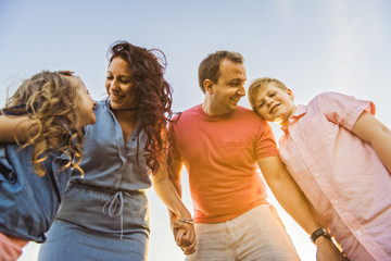 Wall Mural - Happy family having fun on daisy field at sunset