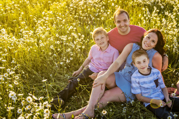 Wall Mural - Happy family having fun on daisy field at sunset