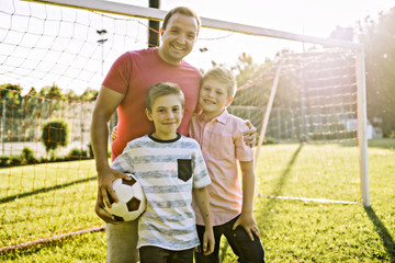 man with child playing football outside on field