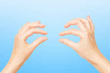 Wall Mural - Female hands holding invisible object isolated at blue background.