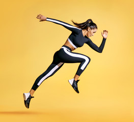 sporty woman runner in silhouette on yellow background. photo of attractive woman in fashionable spo