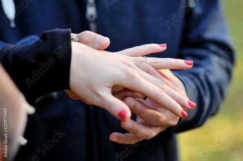 Close-up the male hand puts on a gold engagement ring on a finger of female hand Poster Mural XXL