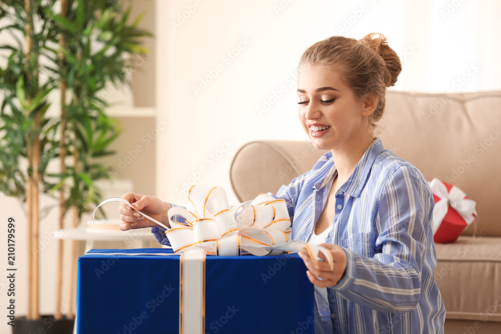 Beautiful young woman with big gift box at home