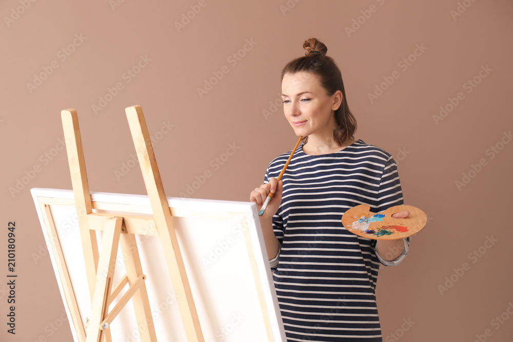 Female artist painting on color background