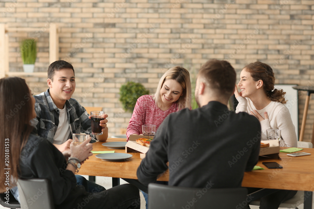 Young people eating pizza at table indoors
