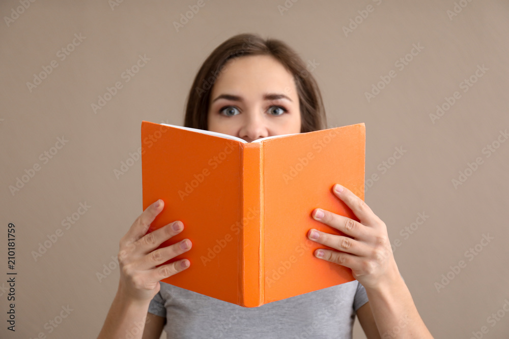 Young woman with book on color background