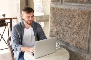 Young freelancer with laptop working in cafe