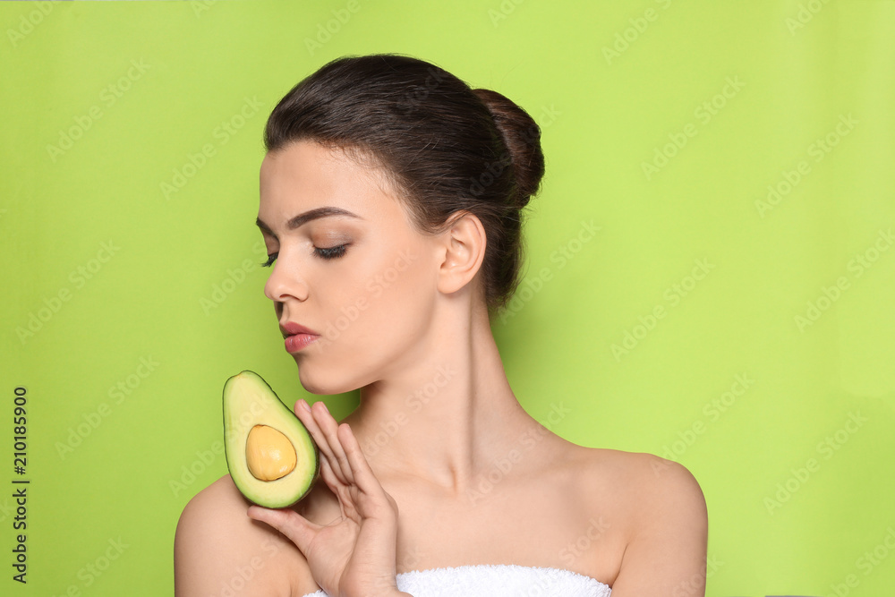 Beautiful young woman with avocado on color background
