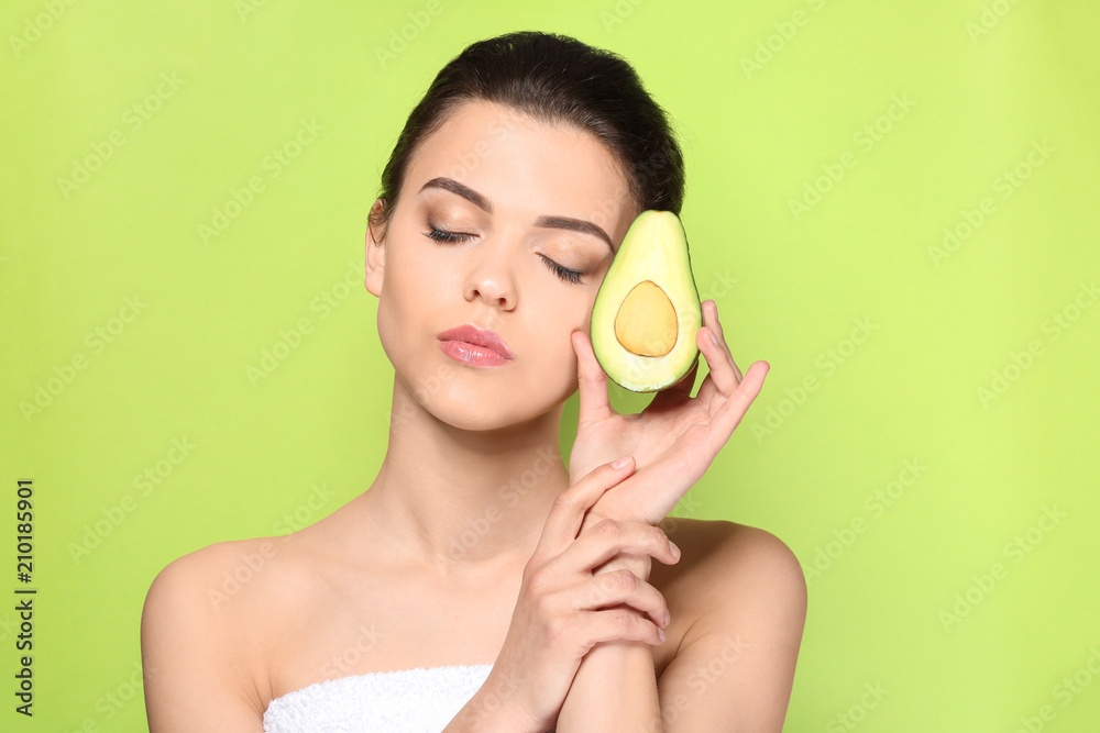 Beautiful young woman with avocado on color background