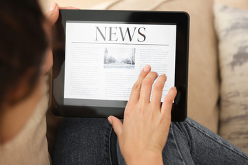 Woman reading news on tablet computer indoors