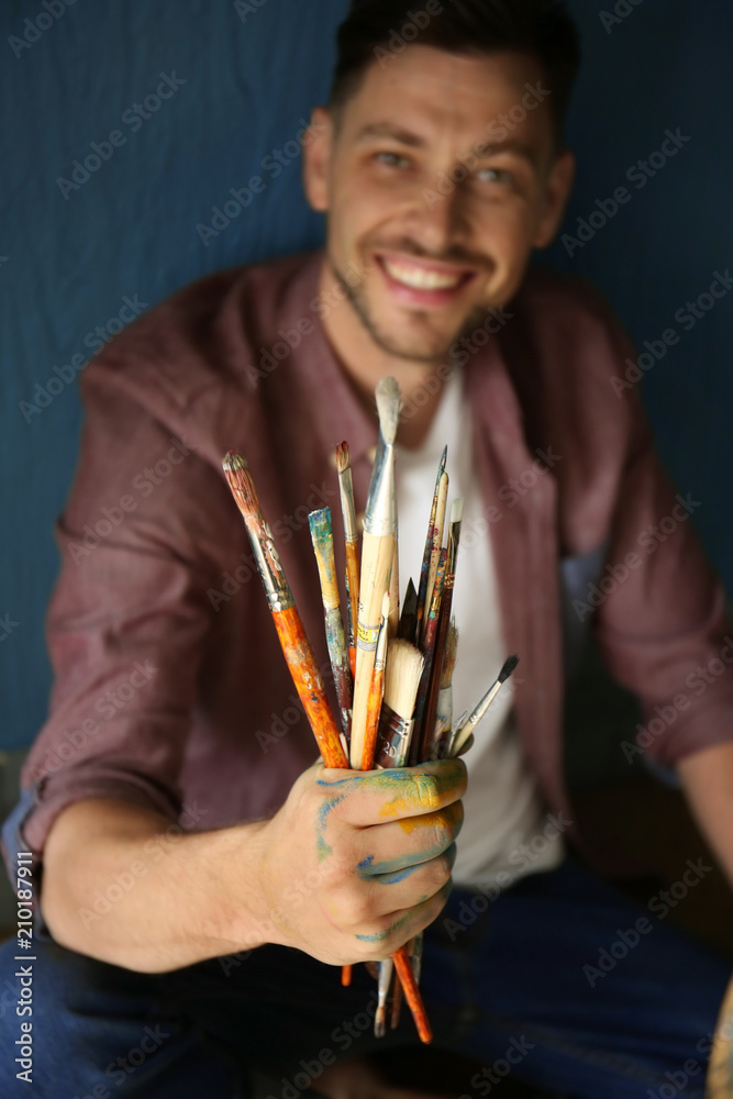 Male artist with paint tools near color wall