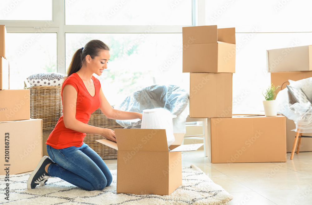 Young woman unpacking box indoors. Moving into new house