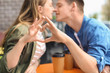 © Pixel-Shot - Happy young couple making heart with their hands while sitting in street cafe
