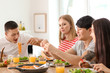 © Pixel-Shot - Friends eating at table in kitchen