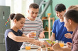 © Pixel-Shot - Friends eating at table in kitchen