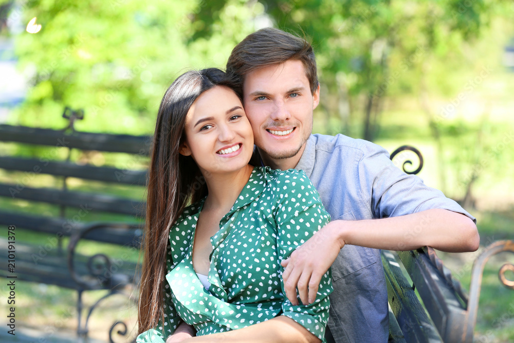 Young couple resting on bench in green park