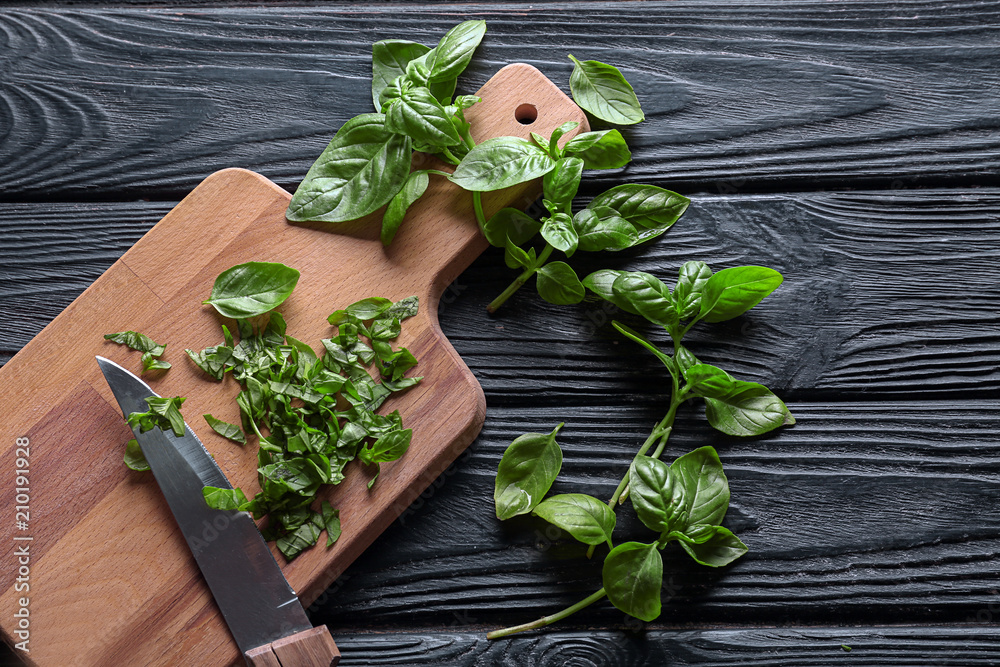 Wooden board with fresh green basil on table