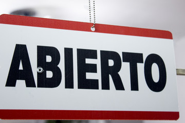 An spanish open sign hanging in a store. Abierto meaning open.